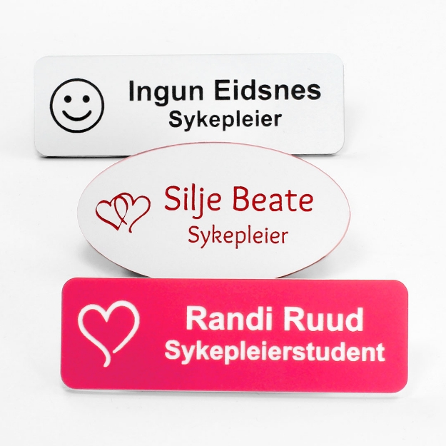 Navneskilt for sykepleier med nål eller magnet. Gravert navneskilt med navn og motiv. Rosa, hvitt, sort og flere farger tilgjengelig.