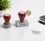 Kontorstempel for bedrift med tekst og logo - Rundt og avlangt stempel med stempeltrykk på papir.